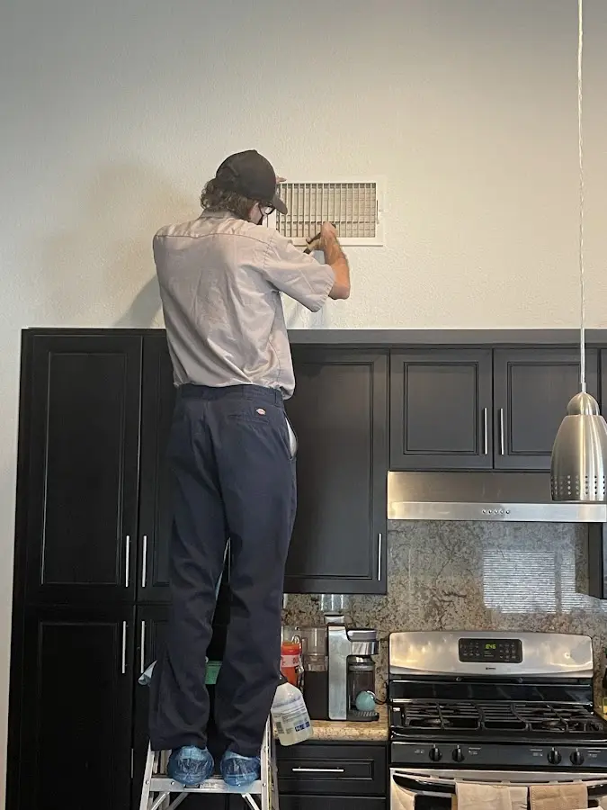 Technician inspecting an air vent during HVAC service in Granby
